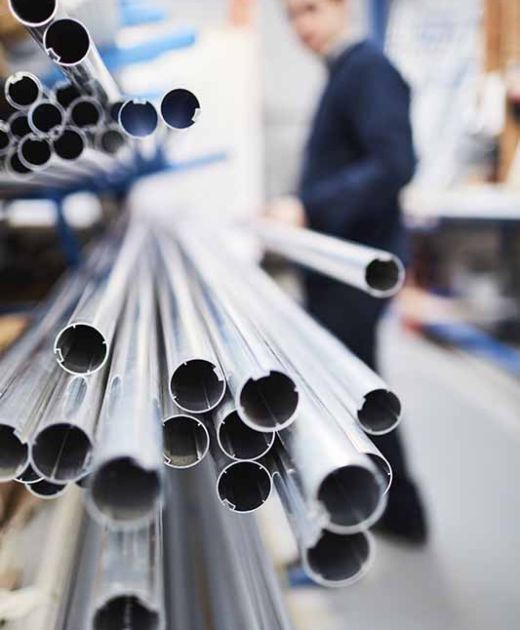 Factory worker removing metal rod from shelf in roller blind factory